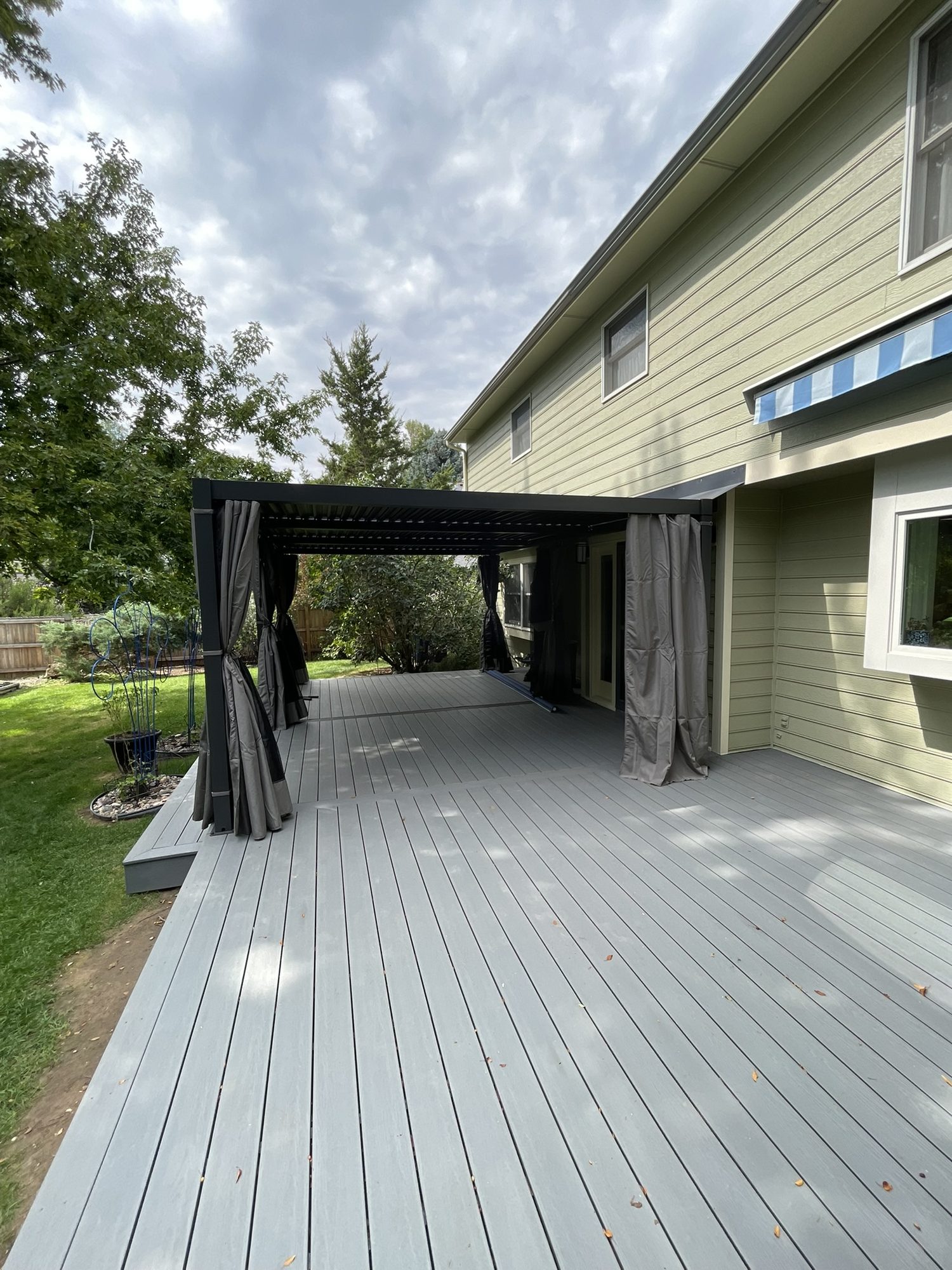 Long gray deck along the back of a house with a pergola at the end