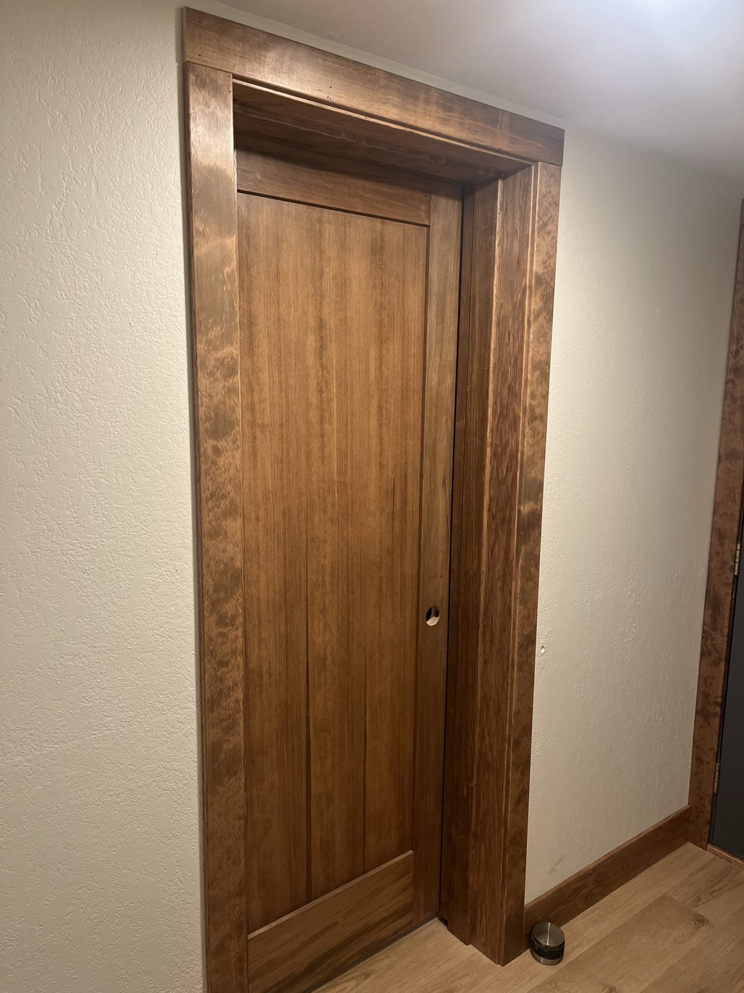 Stained wood interior door with matching casing and baseboard