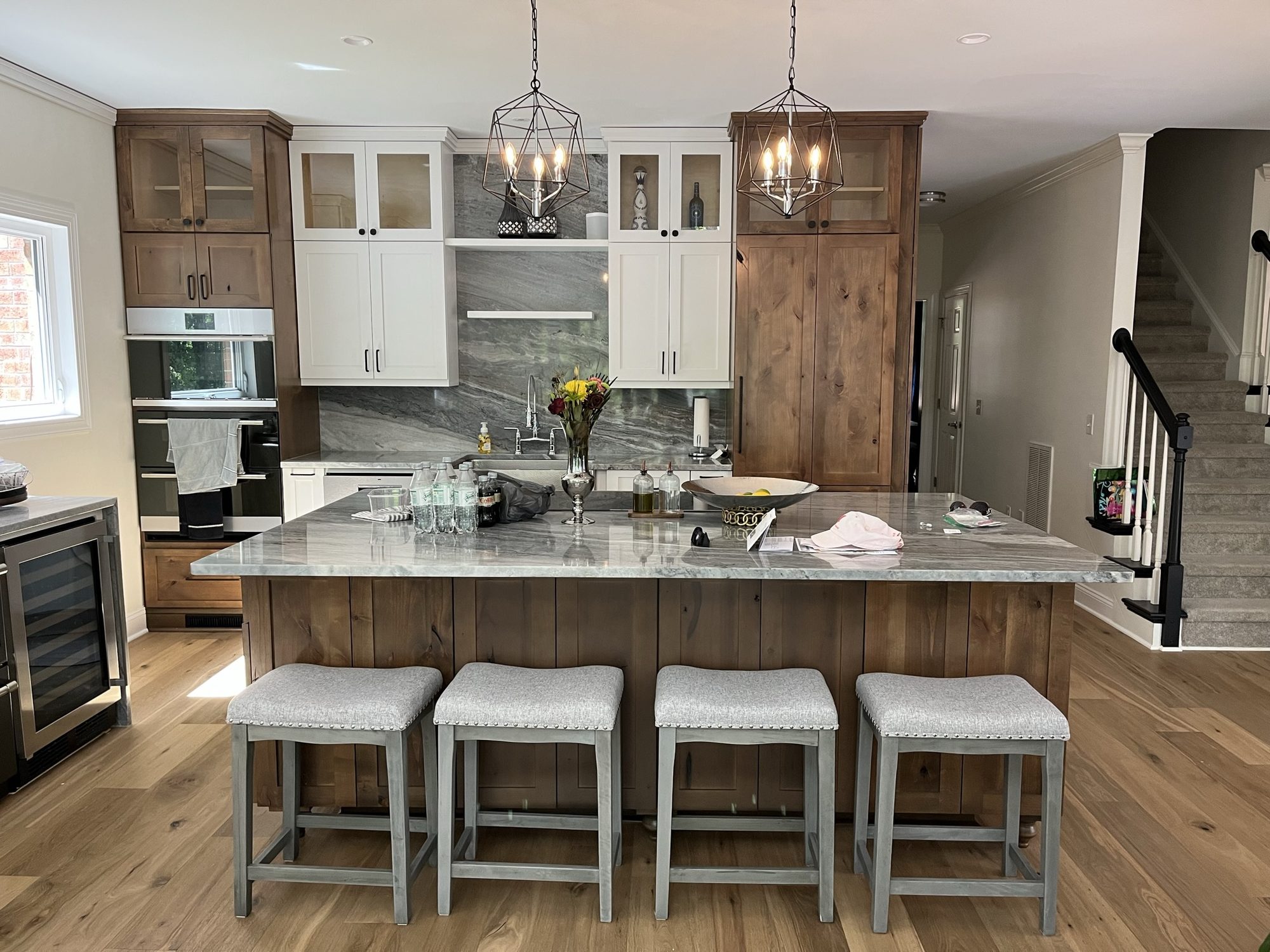 Kitchen with white upper cabinets, knotty alder base cabinets and pantry, and a knotty alder island with seating