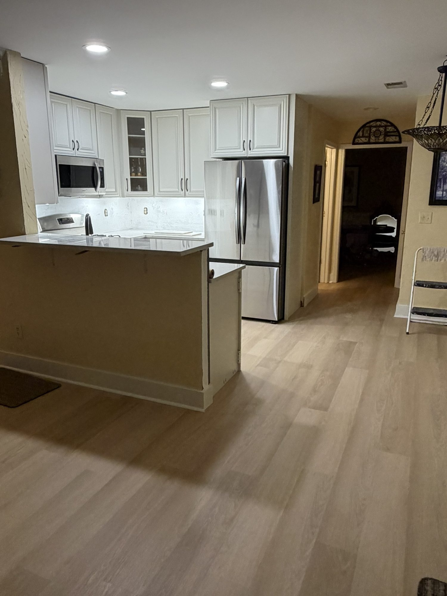 Kitchen peninsula with cream cabinets and wide-plank flooring