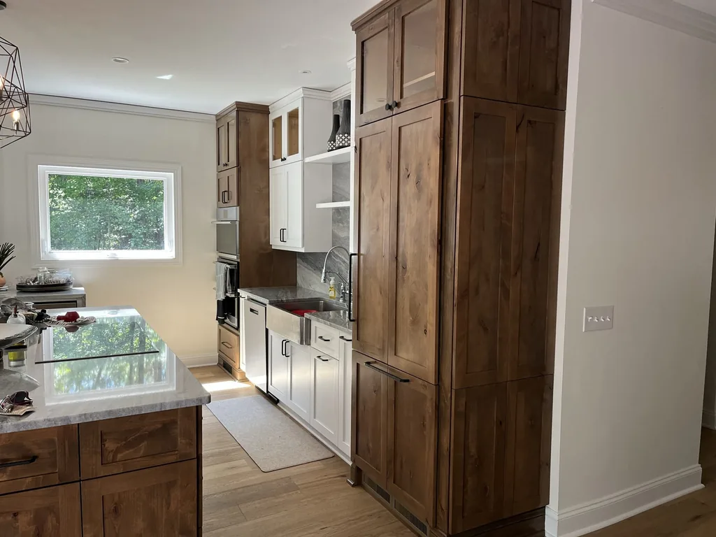 Kitchen with a knotty alder island, white perimeter cabinets and a full-height knotty alder pantry cabinet