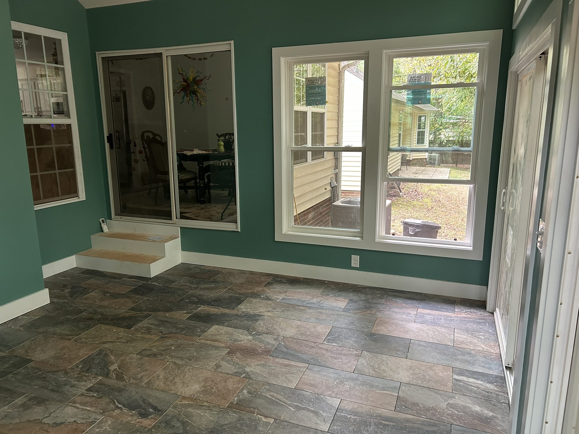 Sunroom with painted walls, window trim and a tile floor